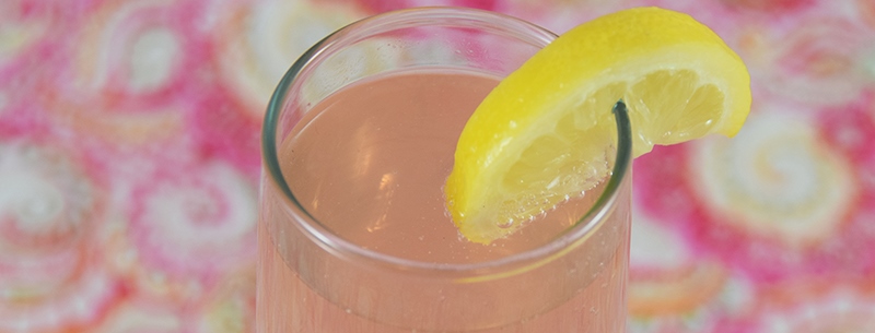 A glass with a slice of lemon on the top of it